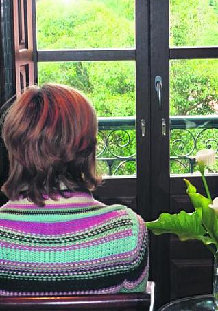 Elisa, de espalda, ante una ventana de su casa.